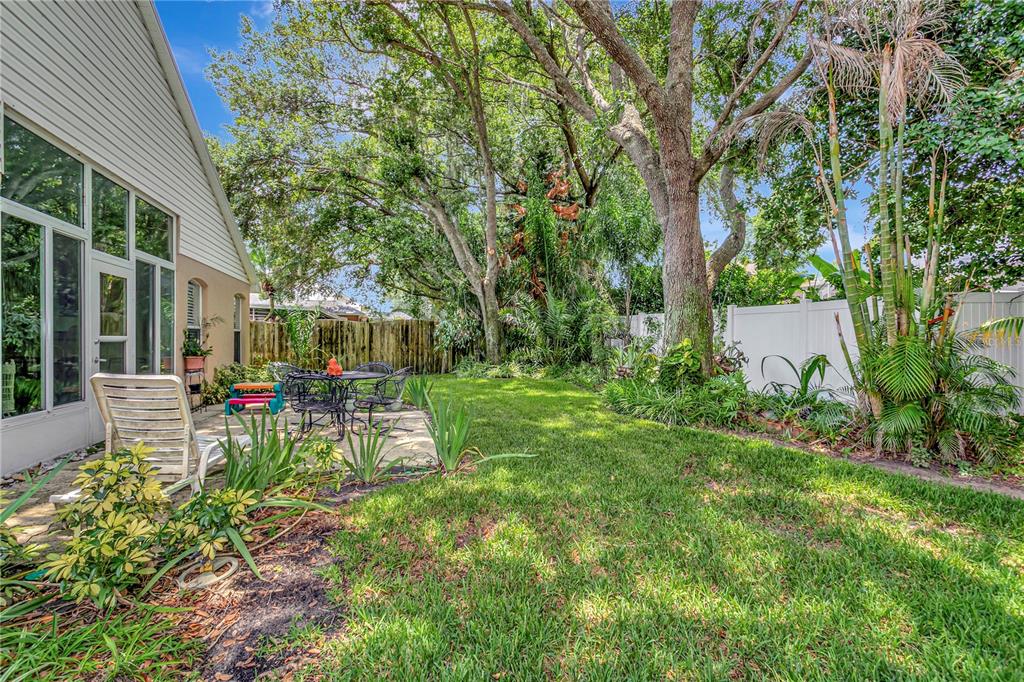 A backyard patio with a table and chairs sits beside a house with large windows — 3049 BEAVER POND TRAIL, VALRICO, FL