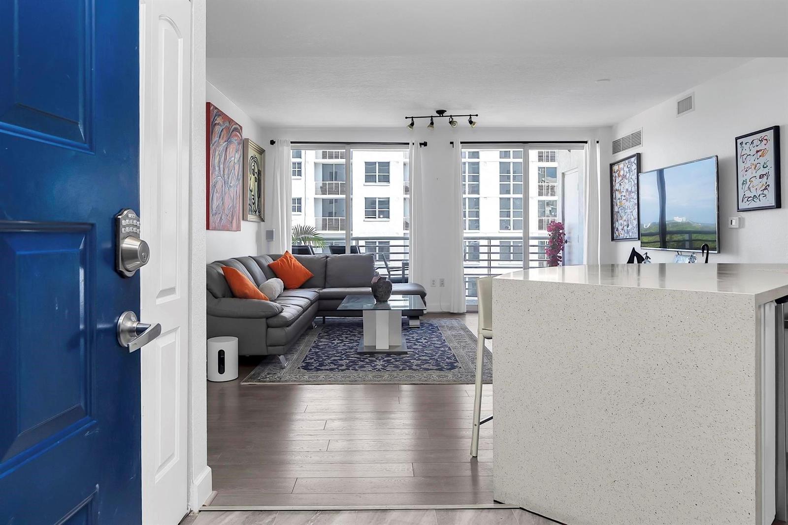 A view from an entryway into a living room with a gray sectional and balcony — 1830 Radius Drive # 912, Hollywood FL 33020, HOLLYWOOD, FL