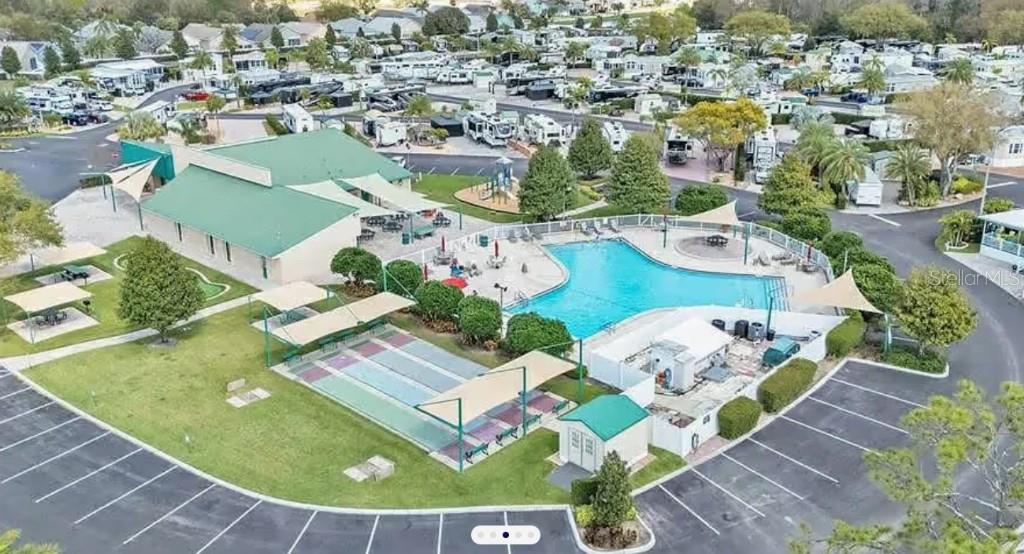 An aerial view of a community pool, clubhouse, and shuffleboard courts in an RV park — 16329 CHERRY TREE COURT, CLERMONT, FL