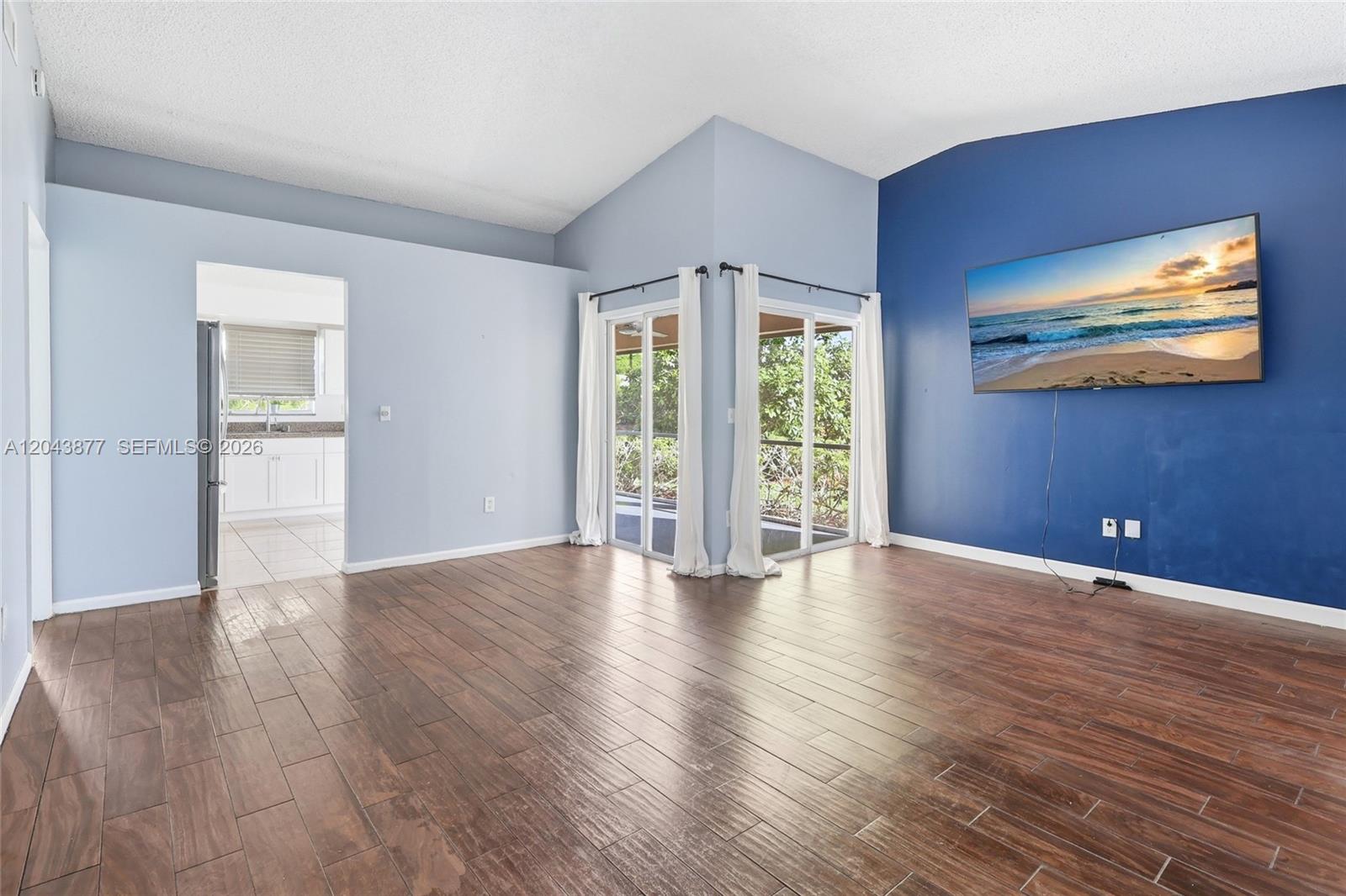 A living room features wood-look tile floors, a blue accent wall, and sliding glass doors — 1855 SE 6th Ct, Homestead FL 33033, HOMESTEAD, FL