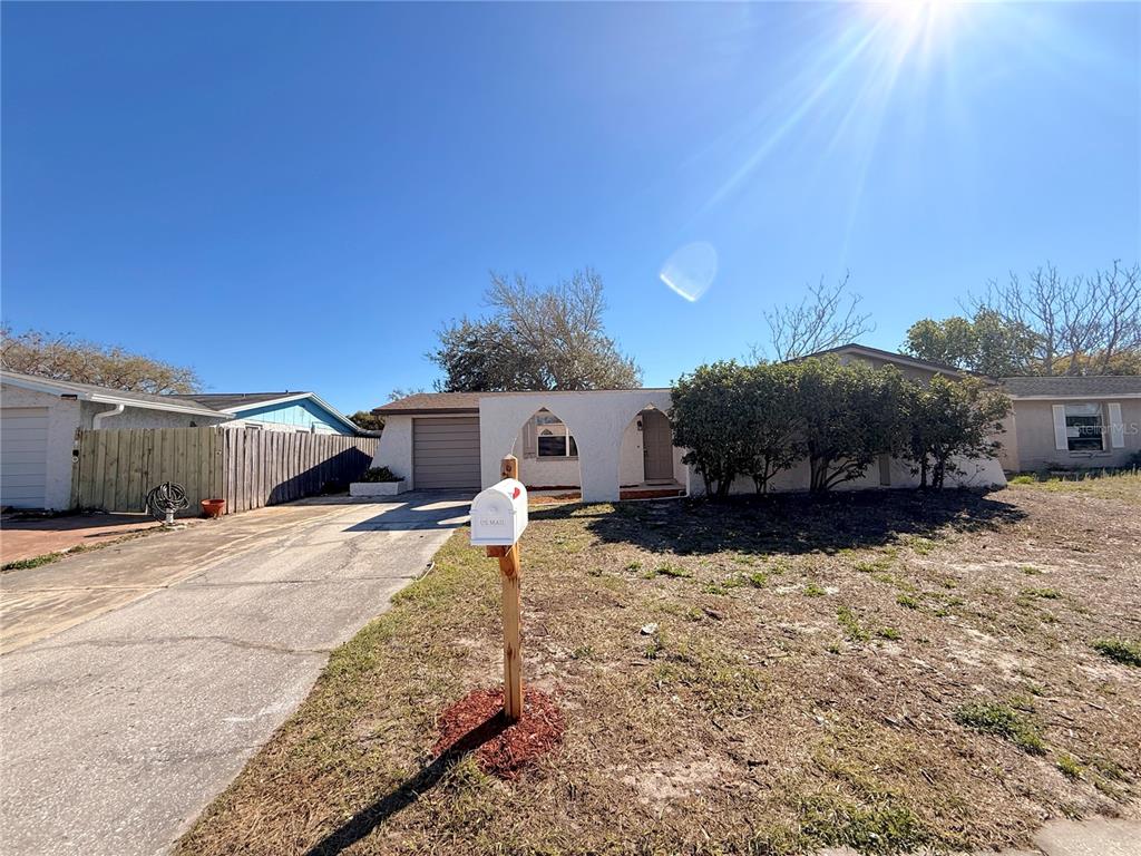 A single-story house with a white stucco facade, arched entryway, and a concrete driveway — 9124 COCHISE LANE, PORT RICHEY, FL