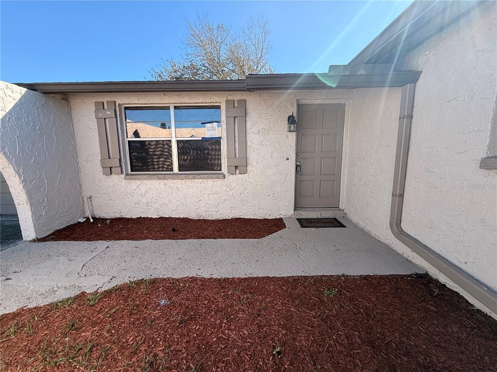 A stucco exterior features a front door, a window with shutters, and a concrete walkway — 9124 COCHISE LANE, PORT RICHEY, FL