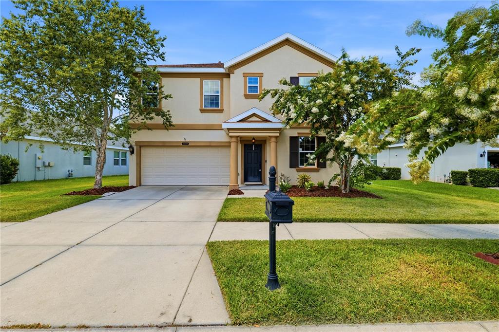 A two-story suburban house with a beige exterior, a two-car garage, and a front lawn — 21439 SOUTHERN CHARM DRIVE, LAND O LAKES, FL