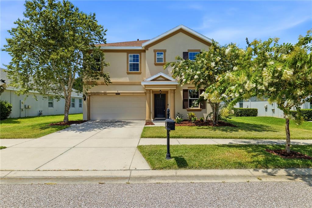 A two-story suburban house with a beige stucco exterior, a garage, and a front lawn — 21439 SOUTHERN CHARM DRIVE, LAND O LAKES, FL