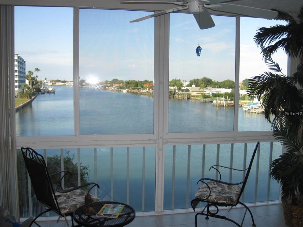 A sunroom with a ceiling fan, two chairs, and a table overlooks a waterfront canal — 105 ISLAND WAY UNIT 138, CLEARWATER BEACH, FL