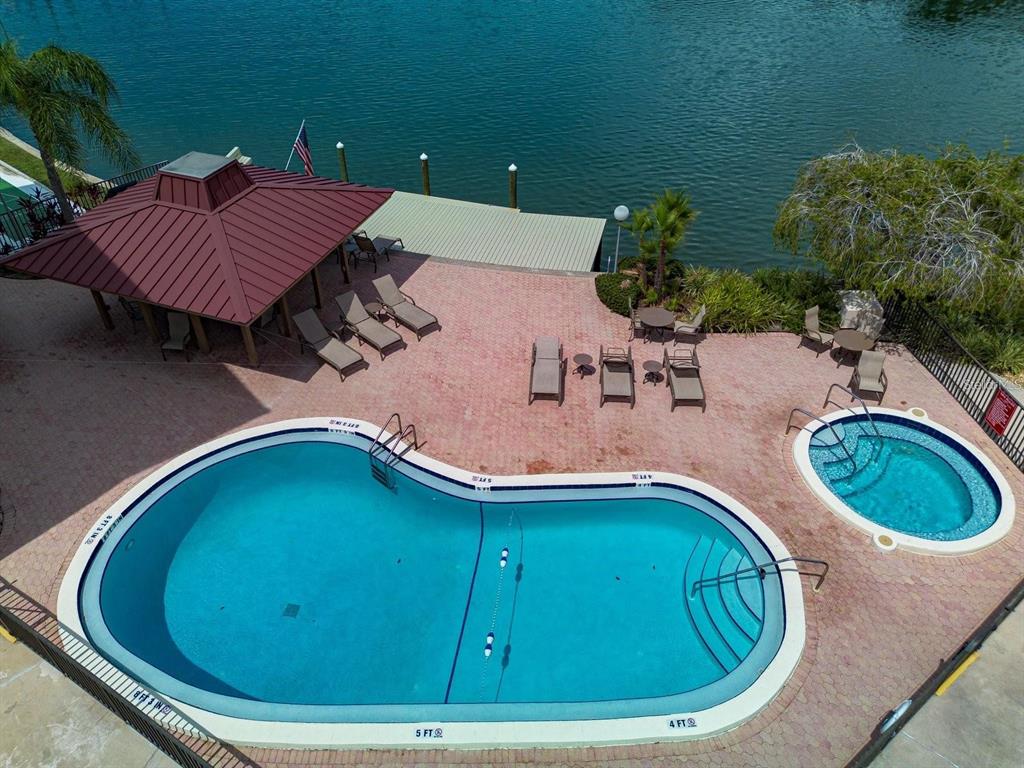 An aerial view shows a swimming pool, a hot tub, and a gazebo by a lake — 105 ISLAND WAY UNIT 138, CLEARWATER BEACH, FL