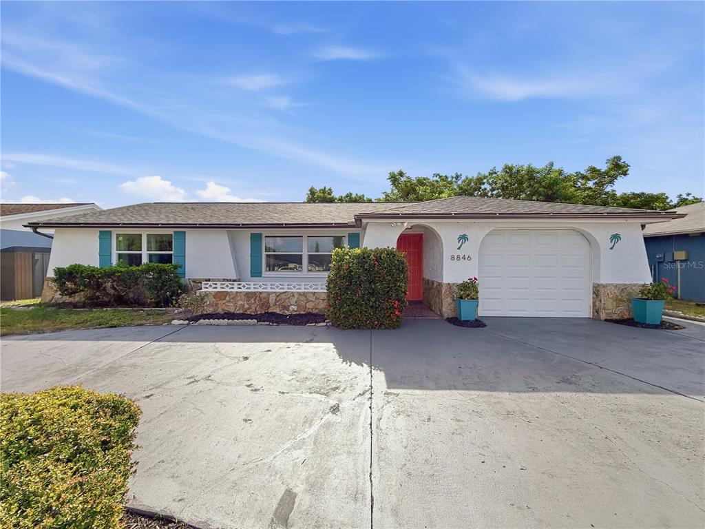 A single-story house with a white exterior, stone accents, a garage, and a concrete driveway — 8846 CARMEN LANE, PORT RICHEY, FL