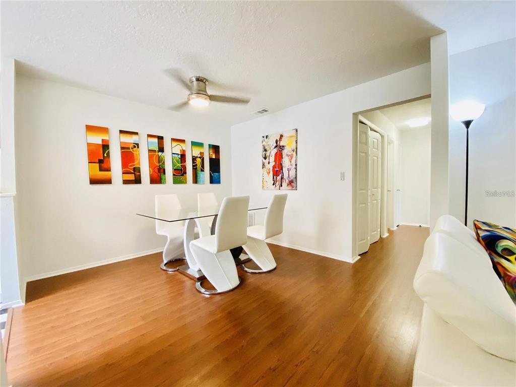 A dining area features a glass table, white chairs, wood flooring, and wall art — 225 S TROPICAL TRAIL UNIT 312, MERRITT ISLAND, FL