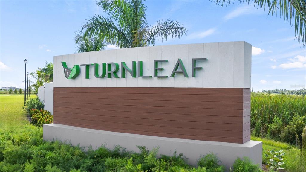 A large, modern monument sign for Turnleaf stands outdoors surrounded by green landscaping and palm trees — 13021 MOONRISE LANE, PUNTA GORDA, FL