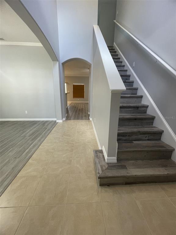 A staircase with wood-look treads leads upward next to a tiled entryway and gray flooring — 2827 SUNCOAST LAKES BOULEVARD, PUNTA GORDA, FL