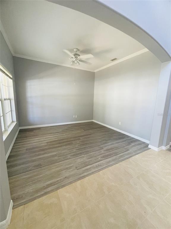 An empty room features gray walls, wood-look flooring, a ceiling fan, and an arched entryway — 2827 SUNCOAST LAKES BOULEVARD, PUNTA GORDA, FL