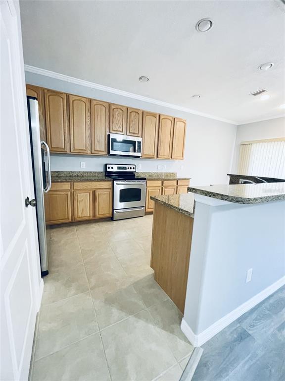 A kitchen features light wood cabinets, granite countertops, stainless steel appliances, and tile flooring — 2827 SUNCOAST LAKES BOULEVARD, PUNTA GORDA, FL