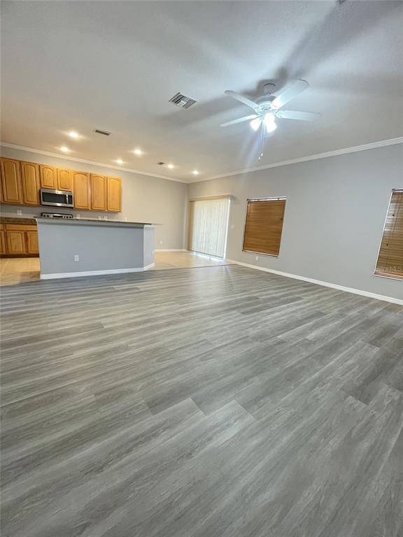 An open-concept living area features gray wood-look flooring, a kitchen with wood cabinets, and recessed lighting — 2827 SUNCOAST LAKES BOULEVARD, PUNTA GORDA, FL