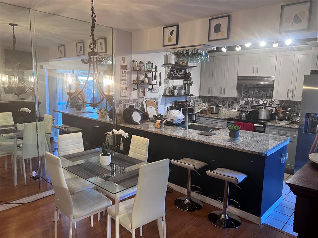 A kitchen with a granite island, white cabinets, and an adjacent dining area with chairs — 2942 POPLAR AVENUE, LEESBURG, FL