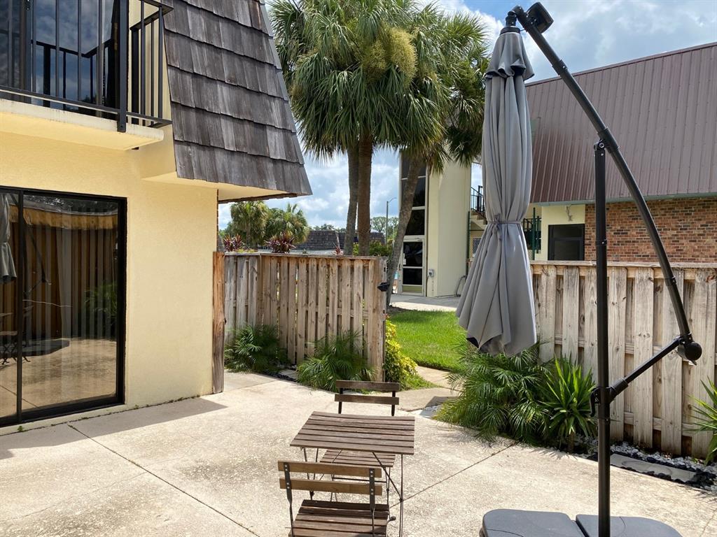 A patio with a wooden table and chairs sits beside a building with a balcony — 2942 POPLAR AVENUE, LEESBURG, FL