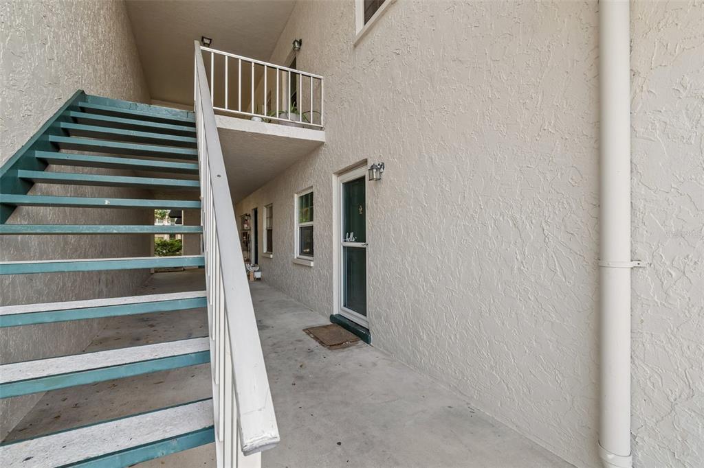 An outdoor staircase leads to an upper-level balcony beside a building with a ground-floor entrance — 4335 AEGEAN DRIVE UNIT 136A, TAMPA, FL