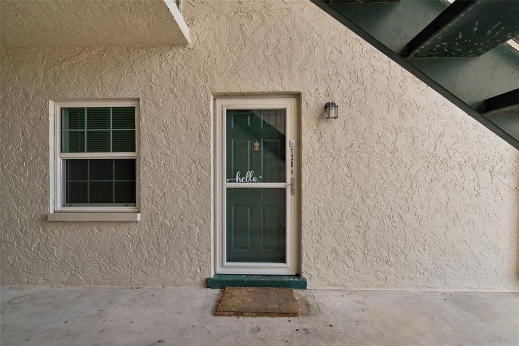 A green front door with a storm door and a window on a stucco wall — 4335 AEGEAN DRIVE UNIT 136A, TAMPA, FL