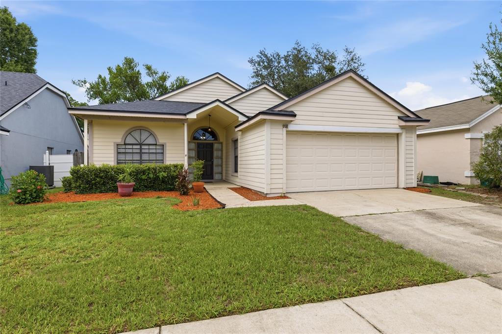 A single-story suburban house with beige siding, a two-car garage, and a front lawn — 718 BIRGHAM PLACE, LAKE MARY, FL