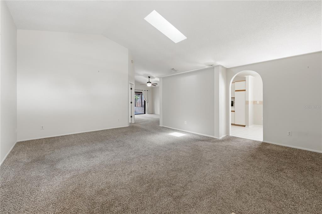 A living and dining area with vaulted ceilings, a skylight, and neutral-toned furniture — 718 BIRGHAM PLACE, LAKE MARY, FL