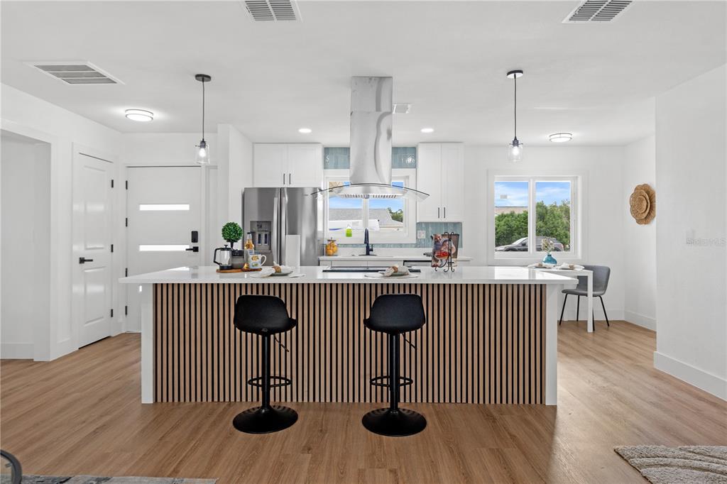 A modern kitchen features a slatted wood island, white cabinetry, and stainless steel appliances — 1406 SETON HALL DRIVE, SUN CITY CENTER, FL