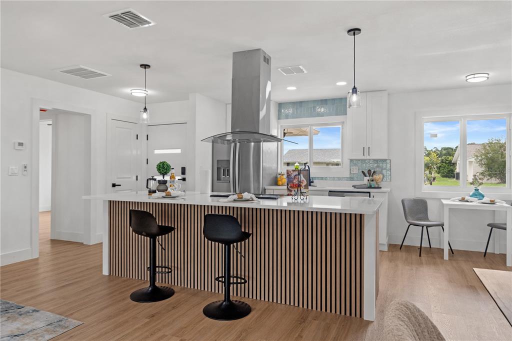A modern kitchen features a slatted wood island, white countertops, and stainless steel appliances — 1406 SETON HALL DRIVE, SUN CITY CENTER, FL
