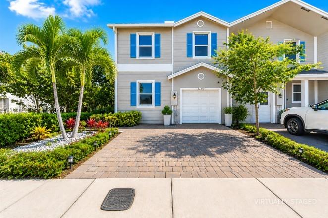 A two-story house with a paved driveway, a white garage door, and palm trees — 1707 SE 9th Ter, Homestead FL 33034, HOMESTEAD, FL