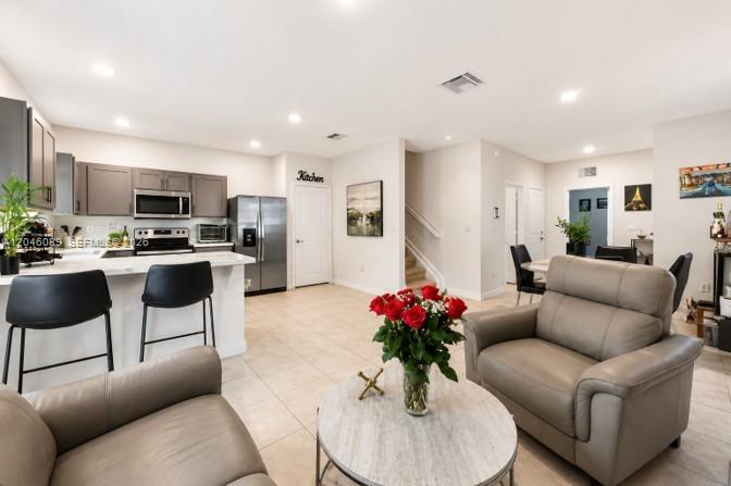 A modern kitchen with gray cabinetry and stainless steel appliances opens into a living area — 1707 SE 9th Ter, Homestead FL 33034, HOMESTEAD, FL