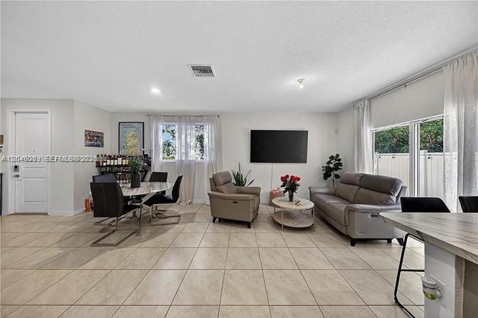 A spacious living room features tile flooring, a mounted television, and a dining area — 1707 SE 9th Ter, Homestead FL 33034, HOMESTEAD, FL