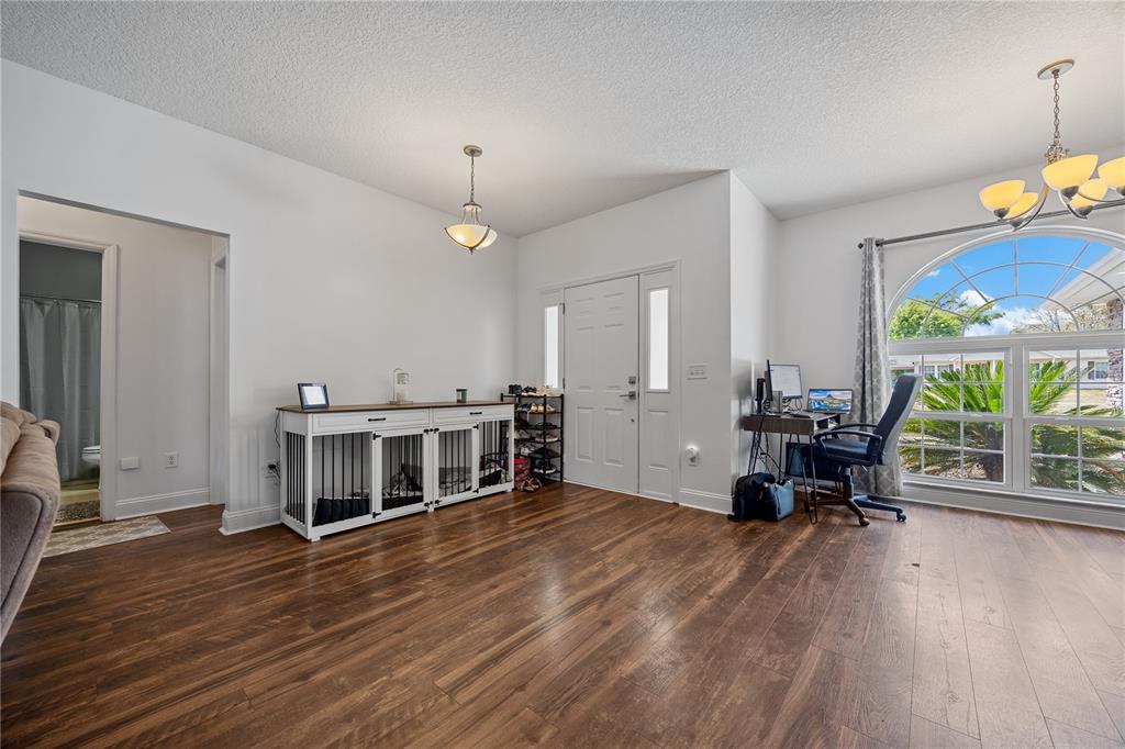 A bright entryway features wood-look flooring, a white front door, and a desk by a window — 9312 SW 152ND COURT, LAKE BUTLER, FL