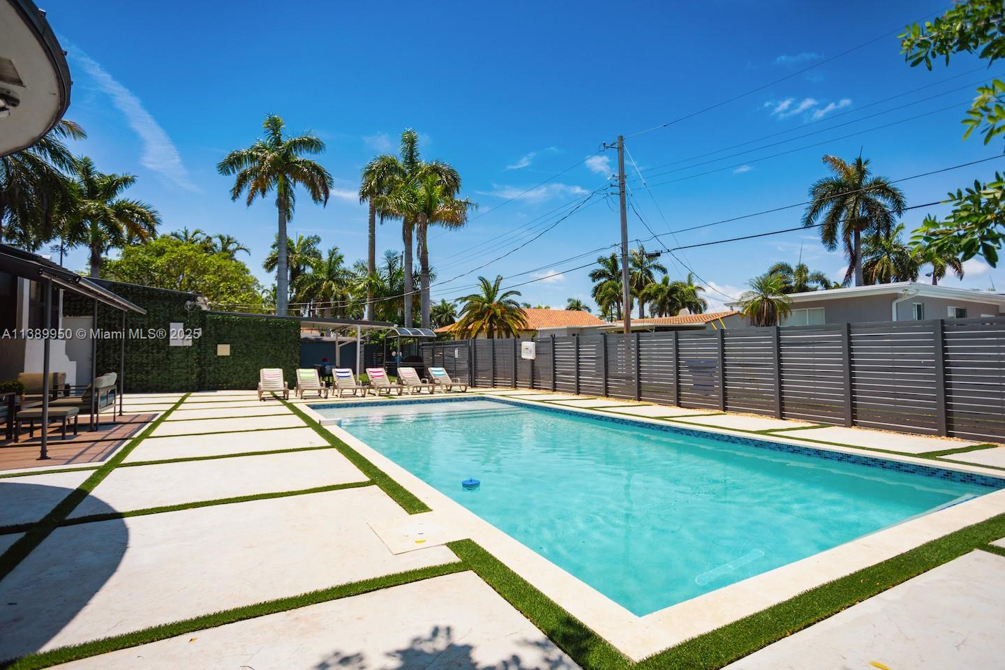 A rectangular swimming pool sits in a backyard with a patio and privacy fence — 801 Harrison St, Hollywood FL 33019, HOLLYWOOD, FL
