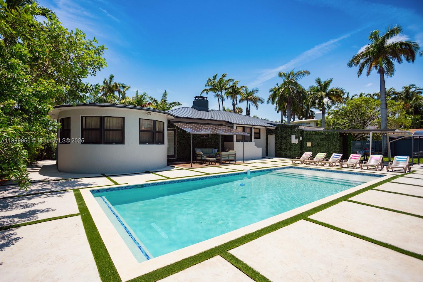 A swimming pool sits in front of a house with a curved wall and patio — 801 Harrison St, Hollywood FL 33019, HOLLYWOOD, FL