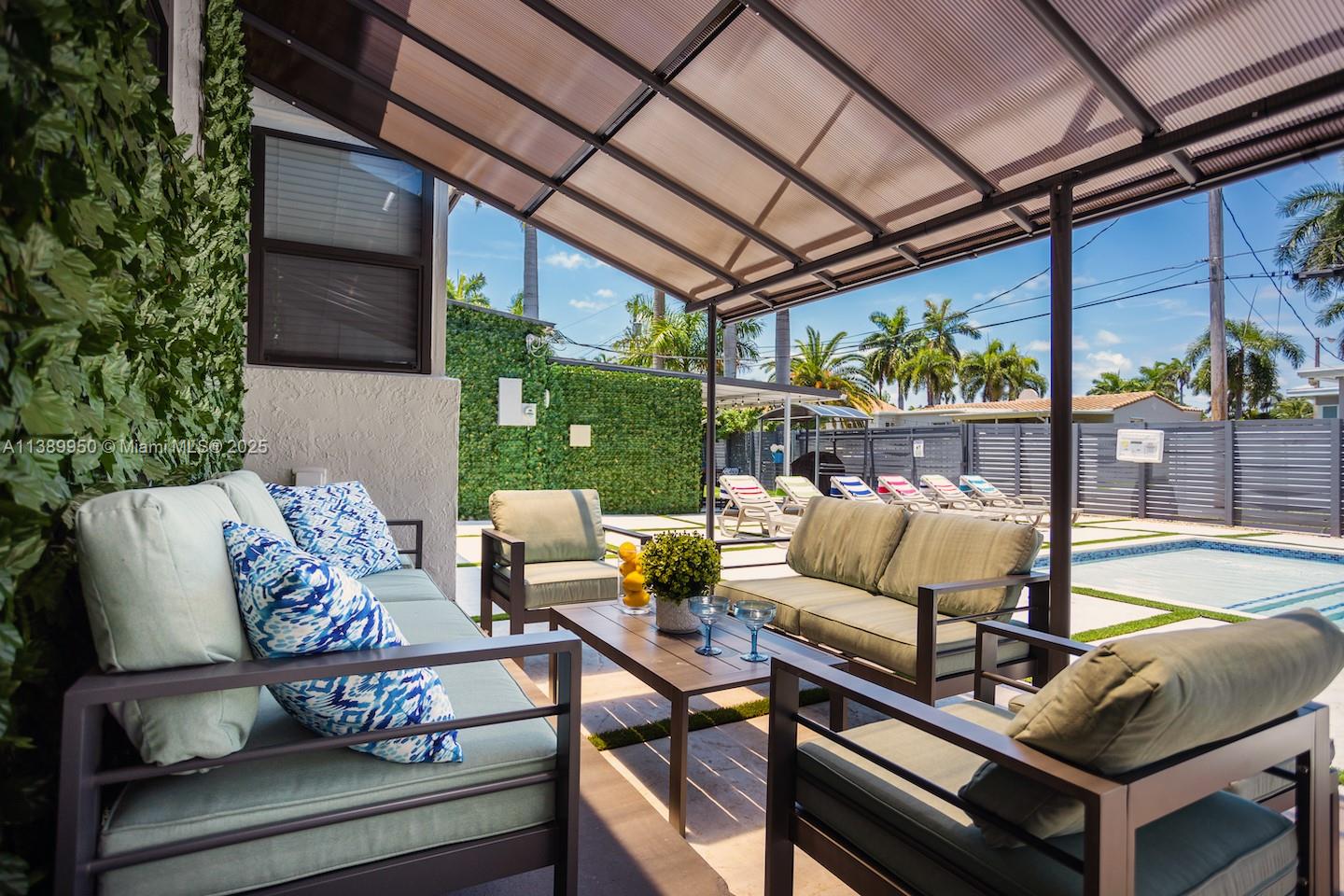 A covered outdoor patio features lounge furniture, a coffee table, and a view of a pool — 801 Harrison St, Hollywood FL 33019, HOLLYWOOD, FL