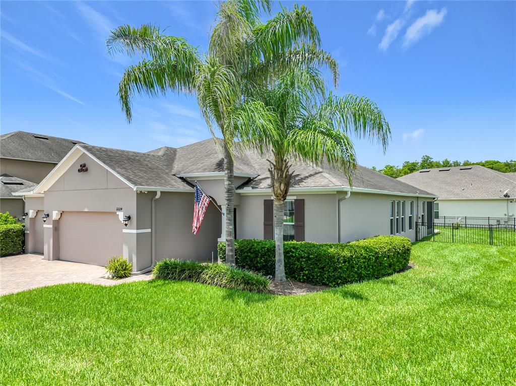 A single-story house with a tan exterior, a two-car garage, and a palm tree — 12224 STONE BARK TRAIL, ORLANDO, FL