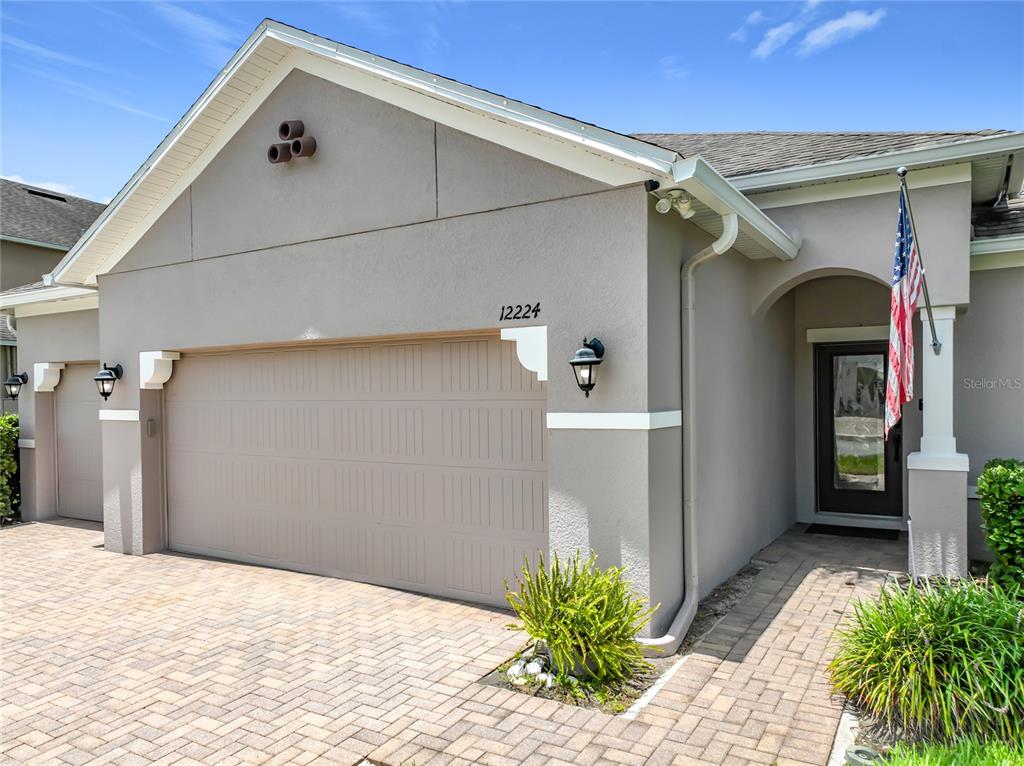 The exterior of a house features a tan stucco facade, a paved driveway, and a garage — 12224 STONE BARK TRAIL, ORLANDO, FL