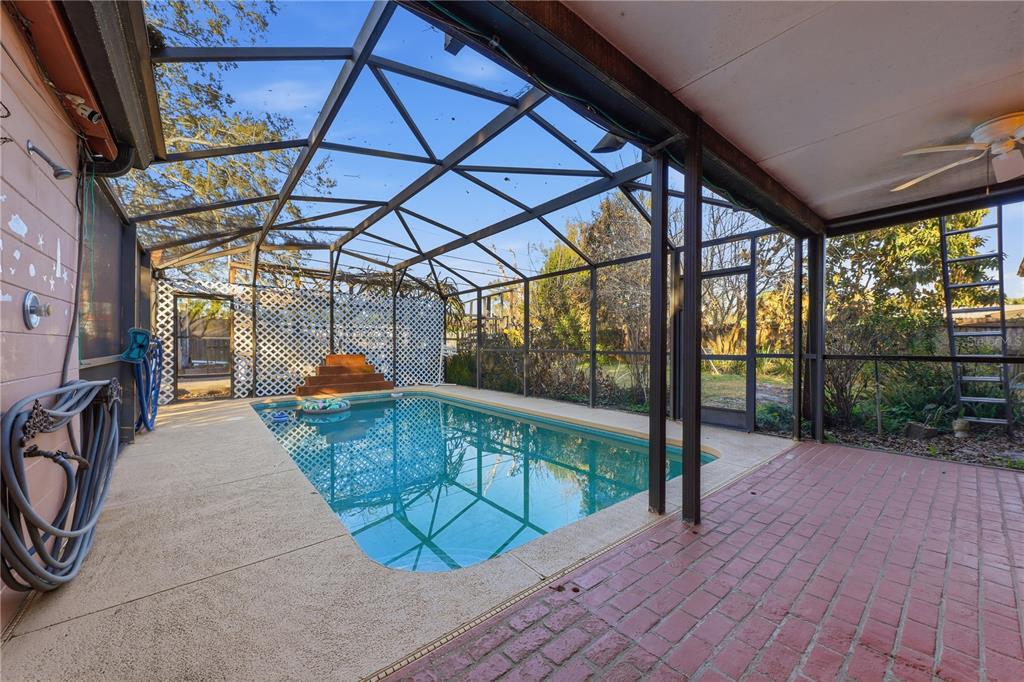 A screened-in pool enclosure features a rectangular swimming pool, concrete decking, and a brick patio — 3809 NEEDLES DRIVE, ORLANDO, FL