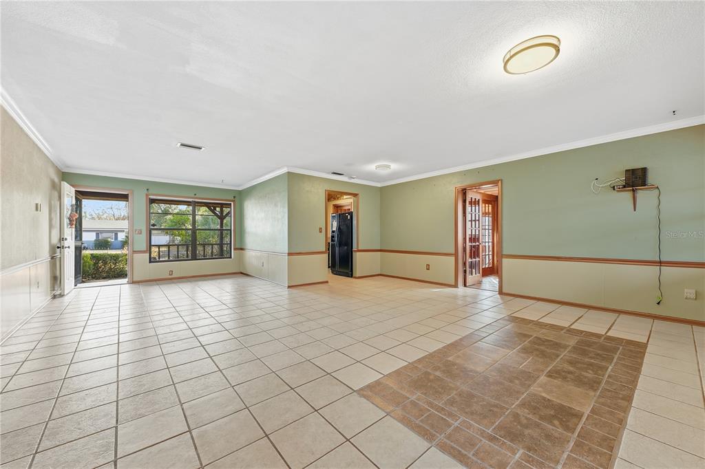 A spacious room with light-colored tile flooring, green walls, and a large window — 3809 NEEDLES DRIVE, ORLANDO, FL