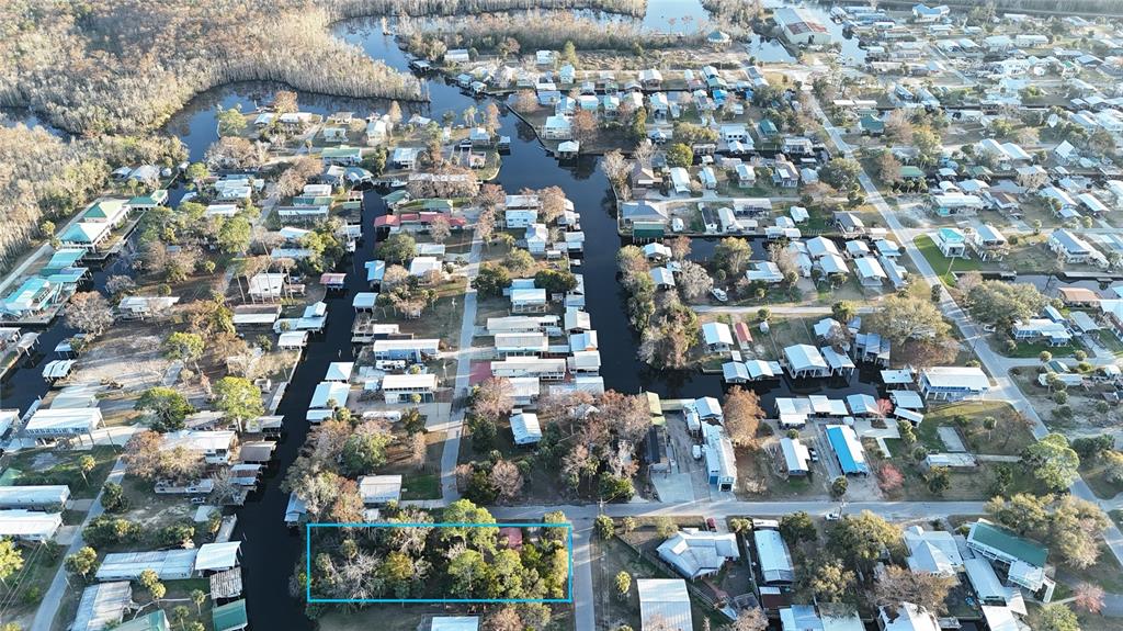 An aerial view shows a wooded, rectangular lot outlined in blue within a canal-front neighborhood — 12 SE 241ST STREET, SUWANNEE, FL