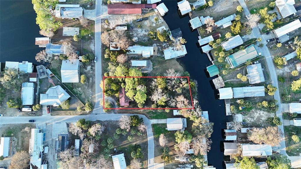 This aerial view shows a residential lot outlined in red situated between a road and canal — 12 SE 241ST STREET, SUWANNEE, FL