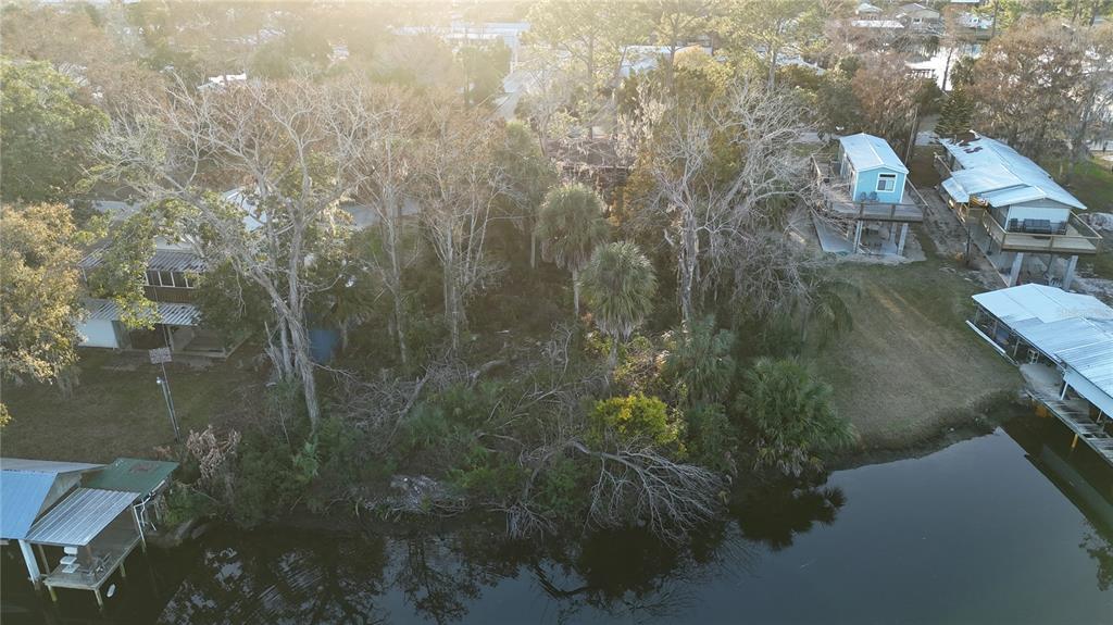 An aerial view shows a wooded waterfront lot situated between several houses and a canal — 12 SE 241ST STREET, SUWANNEE, FL