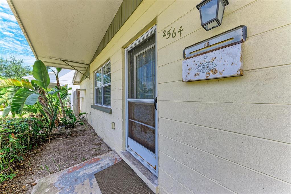 A view of a house exterior featuring a front door, a rusty mailbox, and landscaping — 2564 WOOD STREET, SARASOTA, FL