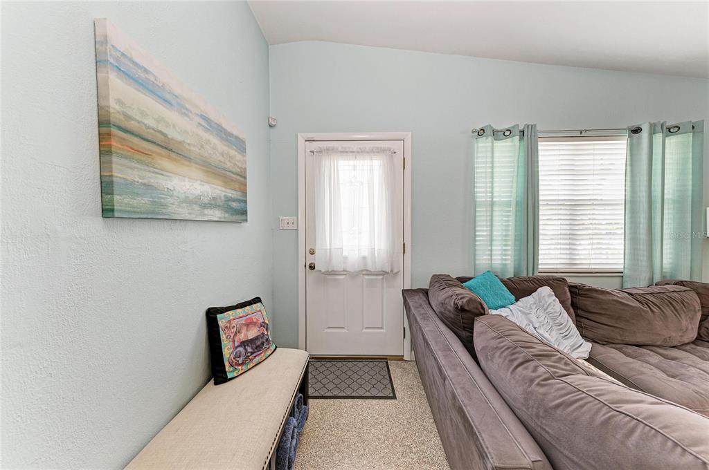 A living room features a beige bench, a brown sectional sofa, and a white door — 2564 WOOD STREET, SARASOTA, FL