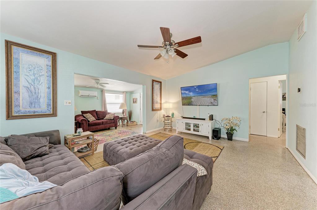 A living room with light blue walls, a grey sectional sofa, and a ceiling fan — 2564 WOOD STREET, SARASOTA, FL