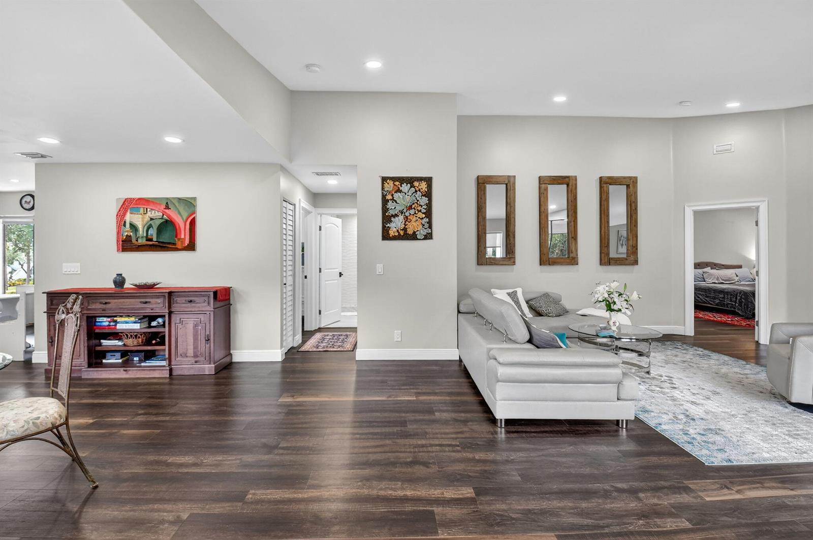 A living room features dark wood flooring, a grey sectional sofa, and three wall-mounted mirrors — 15307 Strathearn Drive # 11204, Delray Beach FL 33446, DELRAY BEACH, FL