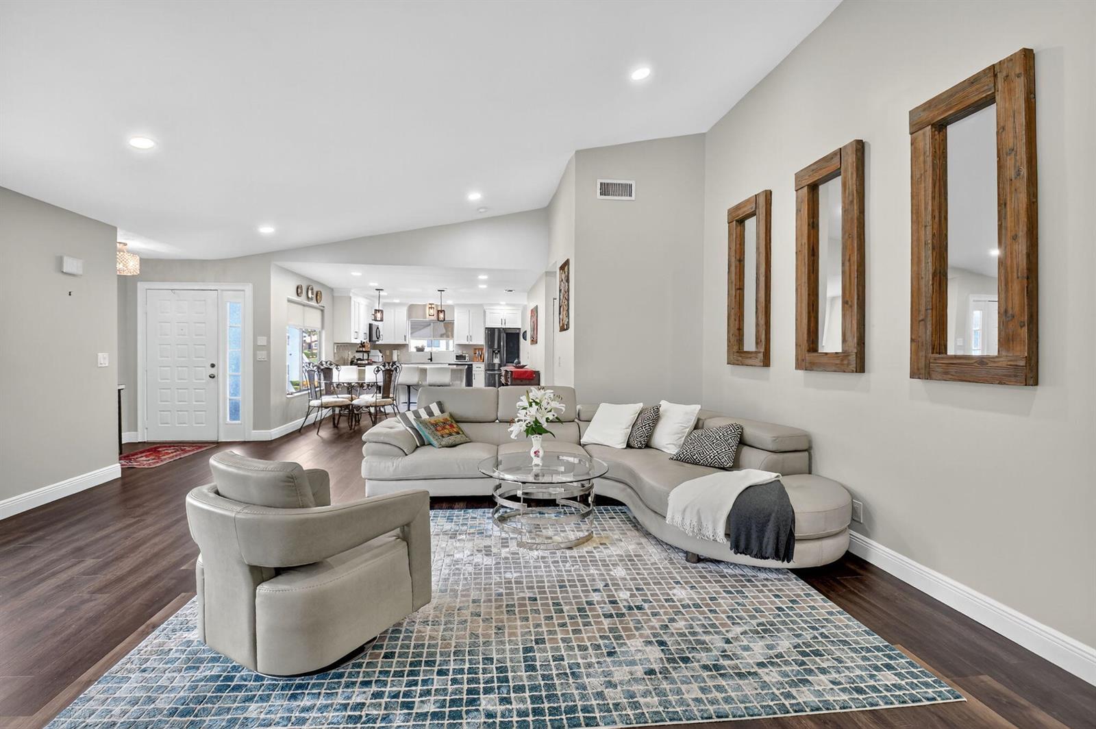 A living room features a curved sectional sofa, a glass coffee table, and three wall mirrors — 15307 Strathearn Drive # 11204, Delray Beach FL 33446, DELRAY BEACH, FL