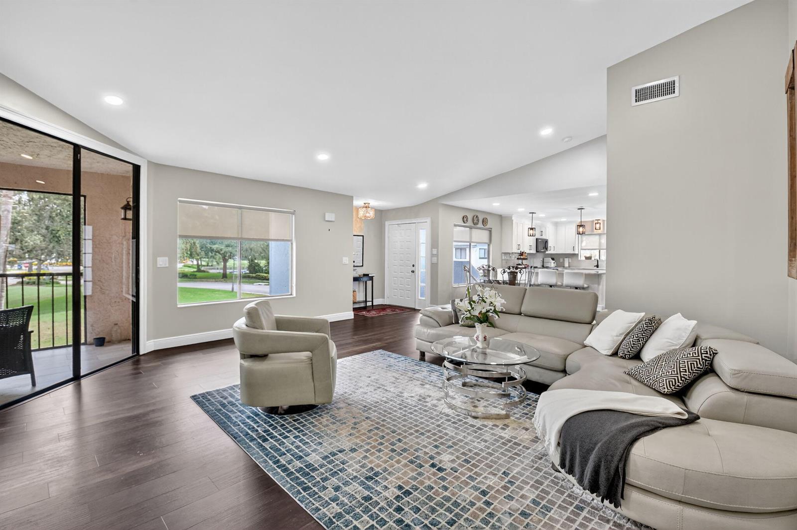 A living room features a sectional sofa, a glass coffee table, and dark wood flooring — 15307 Strathearn Drive # 11204, Delray Beach FL 33446, DELRAY BEACH, FL