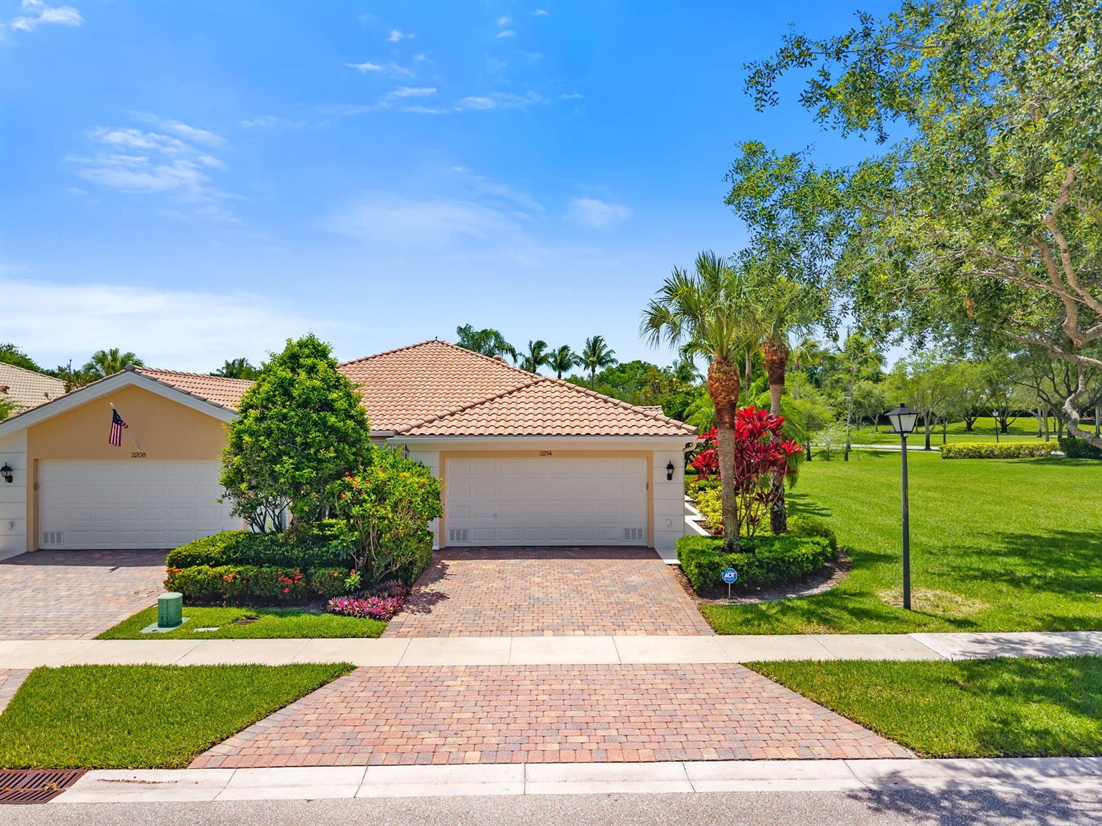 An exterior view of a single-story house with a tiled roof and brick driveway — 3214 Verdmont Lane, Wellington FL 33414, WELLINGTON, FL
