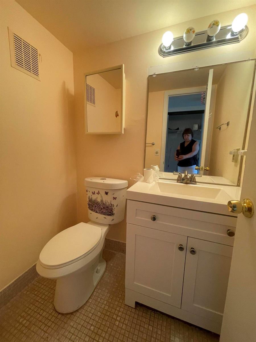 A small bathroom features a white vanity, a toilet with floral decals, and a wall mirror — 522 Tilford X # 522, Deerfield Beach FL 33442, DEERFIELD BEACH, FL