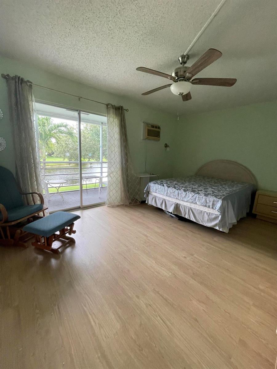 A bedroom with light wood flooring, a ceiling fan, a bed, and a sliding glass door — 522 Tilford X # 522, Deerfield Beach FL 33442, DEERFIELD BEACH, FL