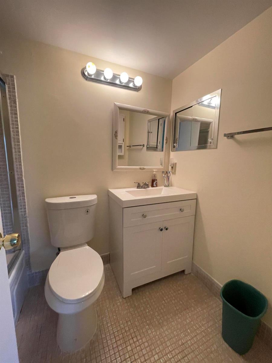 A bathroom features a white vanity, a toilet, a mirror, and a wall-mounted light fixture — 522 Tilford X # 522, Deerfield Beach FL 33442, DEERFIELD BEACH, FL