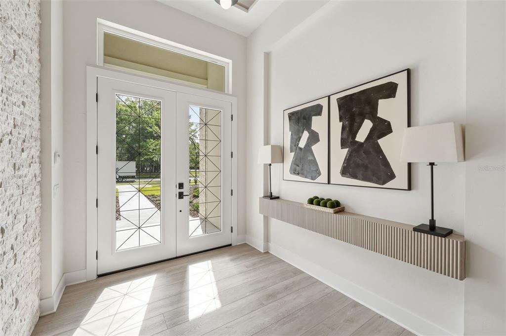 A bright entryway features double glass-paneled doors, light wood flooring, and a floating wall shelf — 5995 SW 124TH WAY, ARCHER, FL